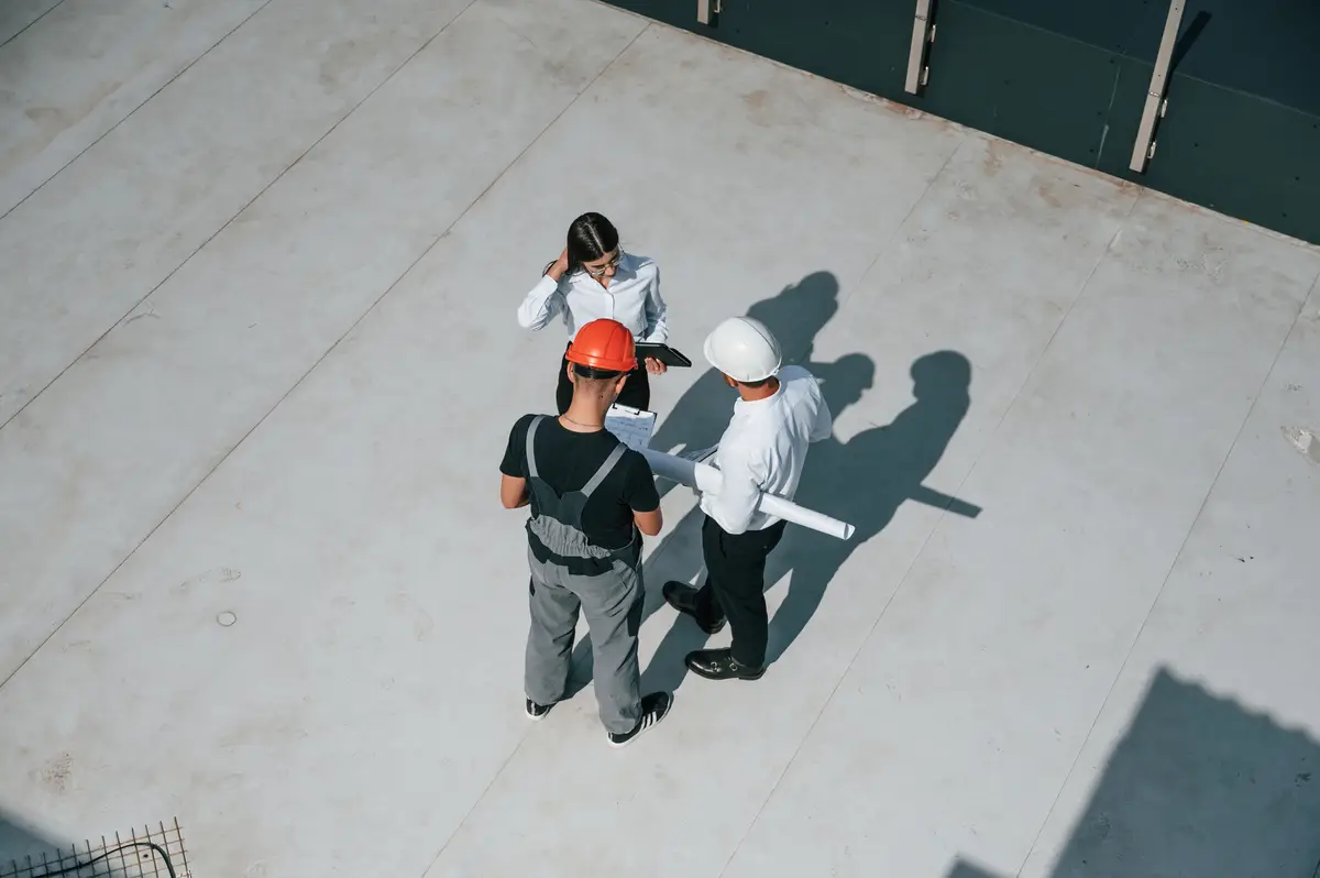 Supervisores de obra con casco revisando planos en sitio