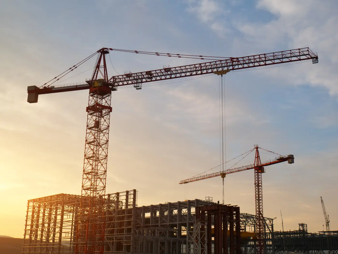 Grúas y estructura de edificio en construcción al atardecer