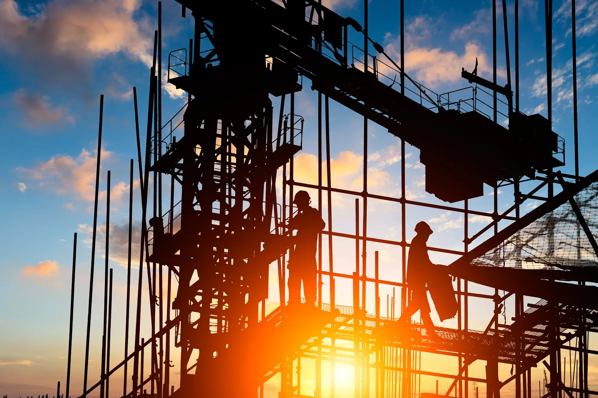 Trabajadores en estructura de obra al atardecer