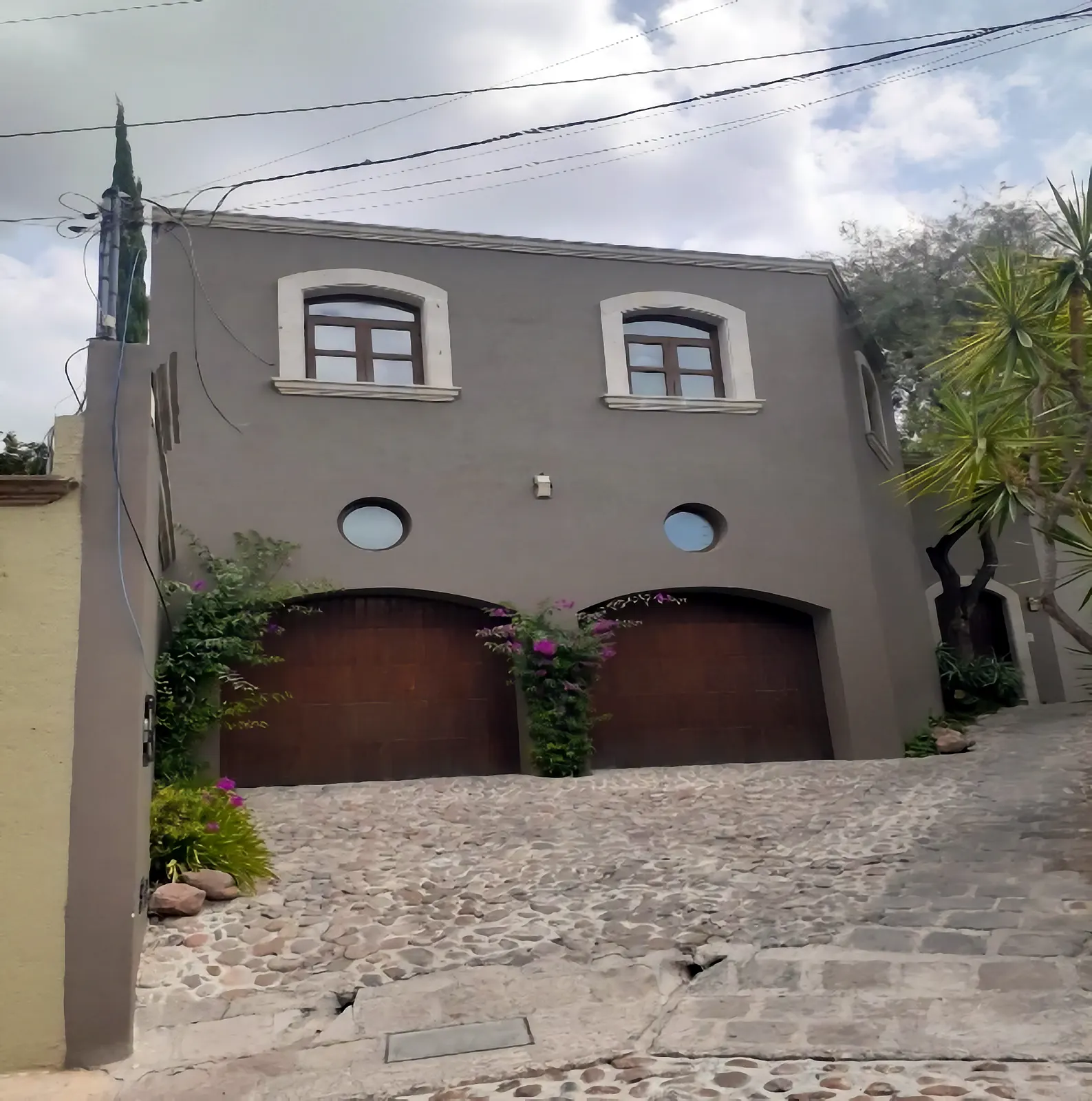 Residencia terminada con fachada aplanada y portones de madera